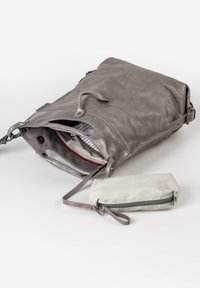 Borsa in pelle grigia con interno con cerniera, dotata di foderatura a righe, un accento rosso e una pochette grigia più piccola attaccata da una cinghia.