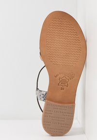Las sandalias de cuero presentan una suela texturada en color marrón, finas correas con un patrón de piel de serpiente y una marca estampada. Talla 38 indicada en la suela.