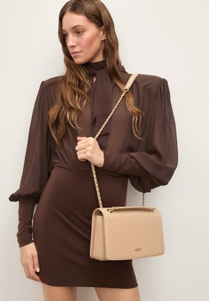 Beige håndtaske med struktureret design, guldfarvet beslag og kæderem. Glat tekstur, rektangulær form og en klaplukning.