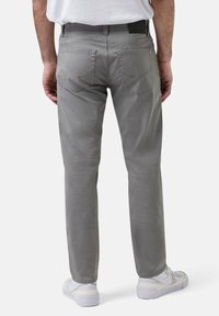 Grijze katoenen broek met een rechte pasvorm, voorzien van twee achterzakken en een label op de tailleband, gecombineerd met witte sneakers.