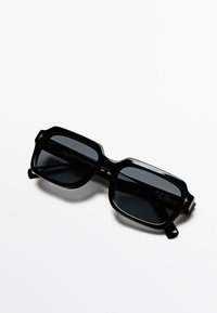 Czarne prostokątne okulary przeciwsłoneczne z ciemnymi soczewkami, plastikową oprawką, kanciastym kształtem i małymi gwiazdkowymi akcentami przy zausznikach.
