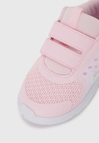 Rosa treningssko med mesh-overdel, borrelås og subtil merkevare. Sålene har en glatt hvit finish med teksturert grep.