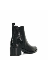Bottines noires avec un motif de serpent texturé, dotées d'une tige en cuir, de panneaux latéraux élastiques et d'un talon épais modéré.