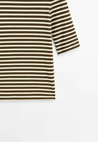 T-shirt à manches longues côtel é avec des rayures horizontales alternées marron foncé et crème. Texture douce avec une coupe décontractée et un col rond.