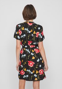 Abito floreale con sfondo nero e fiori rossi, blu e gialli. Maniche corte, vita aderente e orlo fino al ginocchio.