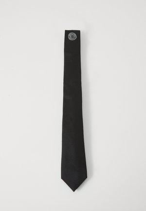 Corbata de satén negro con una textura suave, que presenta un emblema plateado en el extremo estrecho. Diseñada con una forma clásica y esbelta.