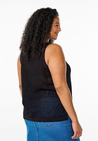 Svart ärmlös topp med en texturerad meshdesign, som har rund halsringning och avslappnad passform, kombinerad med blå denimjeans.