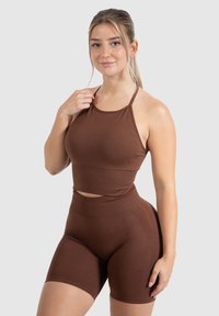 Bruine atletische set met een nauwsluitende, mouwloze crop top met een ronde hals en high-waisted shorts met een zachte textuur.