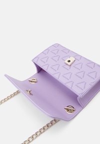 Lila handväska med ett mönstrat inre, guld accenter och en kedja bärrem. Lockstängning som avslöjar två inre fack.
