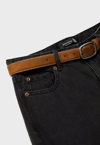 Mustat farkut, joissa on ruskea nahka vyö hopeisen soljen kanssa, viiden taskun muotoilu ja kontrastiväriset tikkausdetailit.