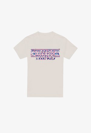 Beige T-Shirt mit glänzendem, metallischem "STRANGER THINGS"-Text in Blau, Lila und Pink, zentriert auf der Vorderseite.
