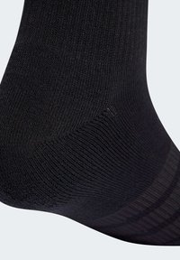 Čierna bavlnená ponožka s textúrovaným dizajnom, ktorá obsahuje rebrovanie a hladký šev na prstoch. Materiál pôsobí mäkko a elasticky.