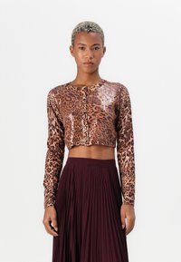 Lepardmønstret langermet cropped topp med blanke paljetter, rund hals, og knappelukking, satt sammen med en plissért burgunder maxi-skjørt.