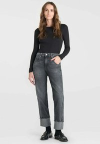 Jeans en denim gris taille haute avec ourlets retroussés, poches avant et coupe droite, associés à un haut noir à manches longues.