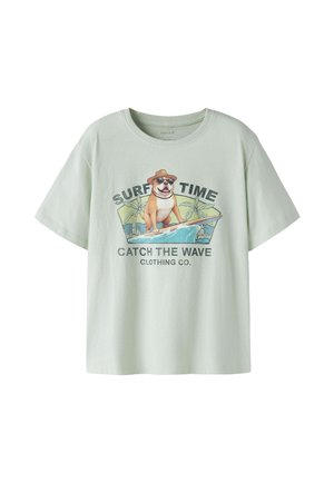 T-shirt vert clair avec un graphisme de chien portant des lunettes de soleil et un chapeau en train de surfer, texte « SURF TIME » et « CATCH THE WAVE CLOTHING CO. »