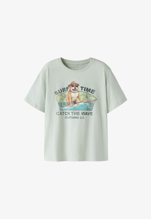 Lichtgroen T-shirt met afbeelding van een hond met zonnebril en hoed die surft, tekst “SURF TIME” en “CATCH THE WAVE CLOTHING CO.”