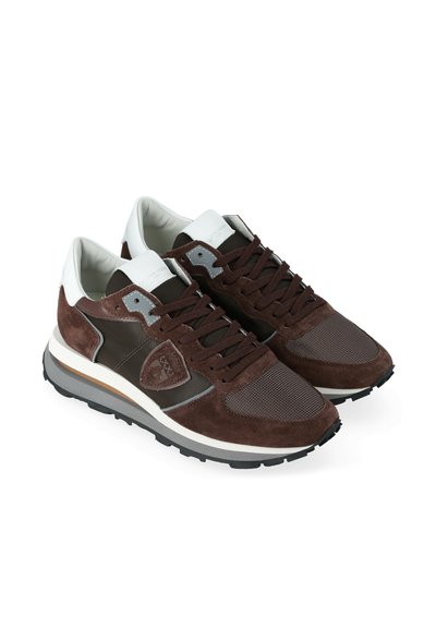 Une paire de baskets en suède et en mesh marron et blanc avec des semelles et des lacets noirs, inclinées pour montrer les côtés intérieur et avant.