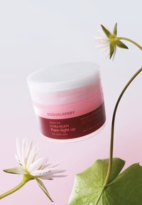 Bouncy Day Collagen Pore-tight w różowym i białym słoiku z tekstem. W tle znajduje się biała kwiat oraz zielony liść.