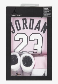 Sættet til babyer består af tre dele: en lyserød skjorte med "JORDAN 23" i sort tryk, samt hvide sokker med sorte accenter og logo.
