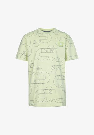 Jasnozielona koszulka z krótkim rękawem w geometryczne czarne wzory, zestawiona z dopasowanymi szortami. Białe sneakersy i paskowane skarpetki dopełniają całość.