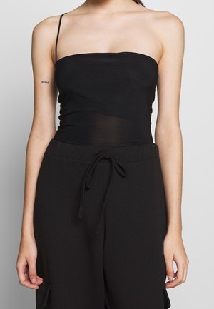 Top noir à bretelles fines avec une coupe ajustée, fabriqué dans un tissu léger et extensible. Il présente une texture lisse et un décolleté droit.