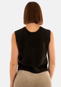 Canottiera senza maniche in maglia marrone scuro con scollatura rotonda, texture morbida e vestibilità comoda, abbinata a pantaloni a coste beige.
