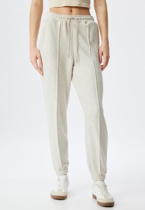 Lichtgrijze, hooggeplaatste joggers gemaakt van zachte stof, voorzien van een trekkoord in de taille, geribbelde boorden en verticale naaddetails.