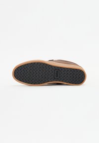 Brown suede shoe with a rubber gum sole, featuring a textured black tread pattern. The shoe has a simple design with no visible logos or accents.