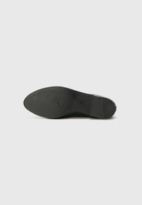 Black rubber shoe sole with a textured pattern, featuring a rounded shape and reinforcements at the heel and toe areas.