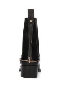 Bottines en cuir noir avec une forme courbée, dotées d'un accent métallique doré et d'un petit talon robuste. Texture lisse et détails minimalistes.
