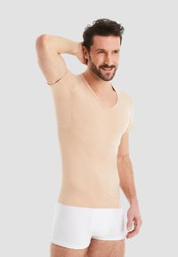Light beige short-sleeve V-neck shirt in a soft fabric, featuring a fitted design and a smooth texture, worn over white underwear.