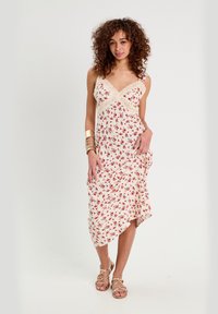 Blumiges Midi-Kleid in Creme mit roten Rosenmustern, Spitzenbesatz am Ausschnitt und Saum, asymmetrischer Schnitt und leichtem Stoff.