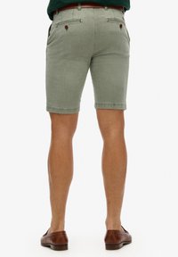 Pantaloni corti di cotone verde chiaro con vestibilità slim, due tasche posteriori e un cintura con passanti. Rifiniti con un orlo pulito e una trama sottile.
