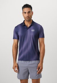 Polo-skjorte i gradient marineblått stoff med kort erm, krage og brodert EA7-logo på brystet. Brukt med lysegrå shorts.