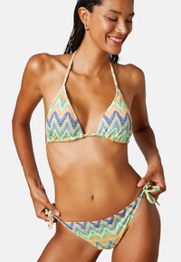 Kolorowy bikini w zygzakowy wzór w odcieniach pomarańczowego, niebieskiego i zielonego. Trójkątny stanik z wiązaniami oraz regulowane wiązania po bokach majtek.