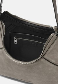 Grijze suede handtas met zwarte leren binnenkant, voorzien van een ritsvak, een gladde textuur en zilverkleurige ritsdetails.