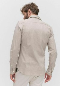 Beige overhemd met lange mouwen, gemaakt van zachte stof, met een puntkraag, knoopmanchetten en een subtiele textuur, gezien vanaf de achterkant.