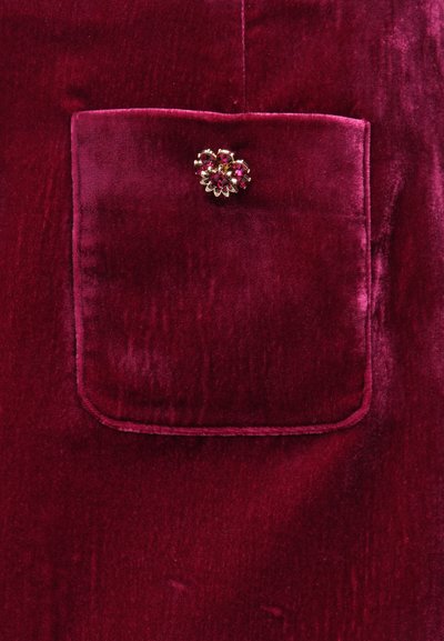 Burgundia sametkangas, millel on ruudukujuline tasku. Taskul on dekoratiivne lillemotiiviga pross roosade ja kuldsete detailidega. Sile tekstuur.