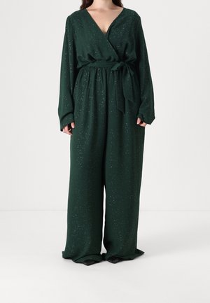 Mørkegrøn, langærmet jumpsuit med vide ben, slå-om front og snøring i taljen, med et subtilt pletmønstret design.