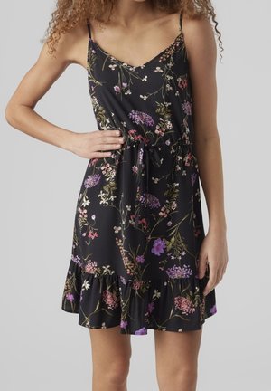 Schwarzblumenkleid mit dünnen Trägern, V-Ausschnitt, tailliertem Bund und Rüschensaum. Es zeigt lila, rosa und grüne Blumenmuster aus einem weichen Stoff.