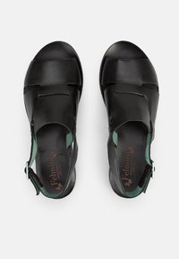 Sandali in pelle nera con dettagli verde menta, caratterizzati da cinturini intagliati e chiusura a fibbia. Suole interne testurizzate con dettaglio del logo.
