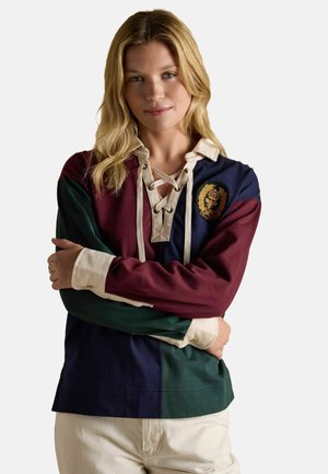 Color-blocked long-sleeve shirt featuring burgundy, navy, green, and cream panels. Lace-up neckline with emblem detail on the chest.