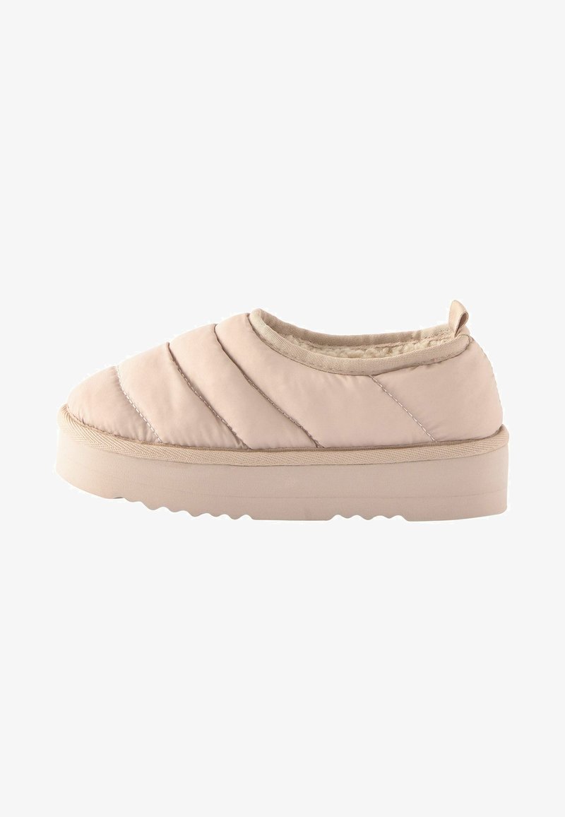 Padded slip-on shoe in light beige, featuring quilted design, round toe, and thick rubber sole with textured bottom for traction.