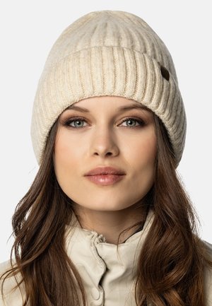 Berretto lavorato a maglia color crema con texture a coste, caratterizzato da un piccolo dettaglio in pelle marrone. Materiale morbido e design a corona arrotondata.