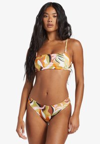 Multicolored bikini set with a bandeau top and low-rise bottoms. Features a wavy abstract pattern in peach, green, and brown tones.