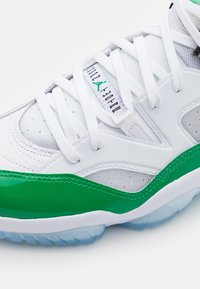 Gros plan sur une chaussure de sport blanche et verte avec des lacets blancs et le logo "Air Jordan" sur la languette.