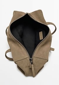 Zaino in suede marrone con apertura con zip, caratterizzato da una foderatura interna nera e un piccolo etichetta all'interno. Due cinghie laterali per il trasporto.