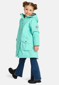 Turkio spalvos vandeniui atsparus parka su gobtuvu, dviem priekinėm kišenėm ir pilku pamušalu. Derinamas su plačiomis džinsomis ir juodais batais.