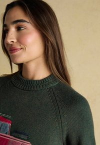 Roheline kudumine särk ribbed ümmarguse kaelusega, millel on värvikas tikand autode kujutis rinnal ja tekstuuriga detailid varrukatel.