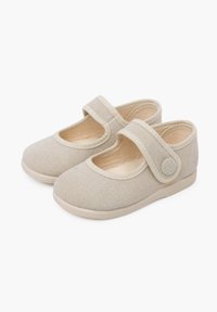 Zapatos de lona beige con punta redonda, tirante elástico en el empeine y suela de goma para tracción. Tejido texturizado y detalles de costura.